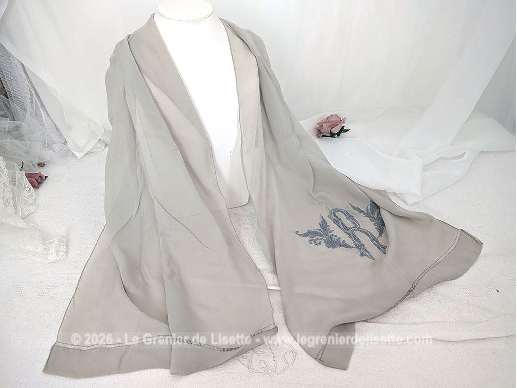 Fait main, voici une écharpe en voile de crêpe gris taupe de 80 x 154 cm, orné d'un grand R brodé et décoré aux extrémités d'un jour de Venise. Pour une écharpe discrète, originale et unique.