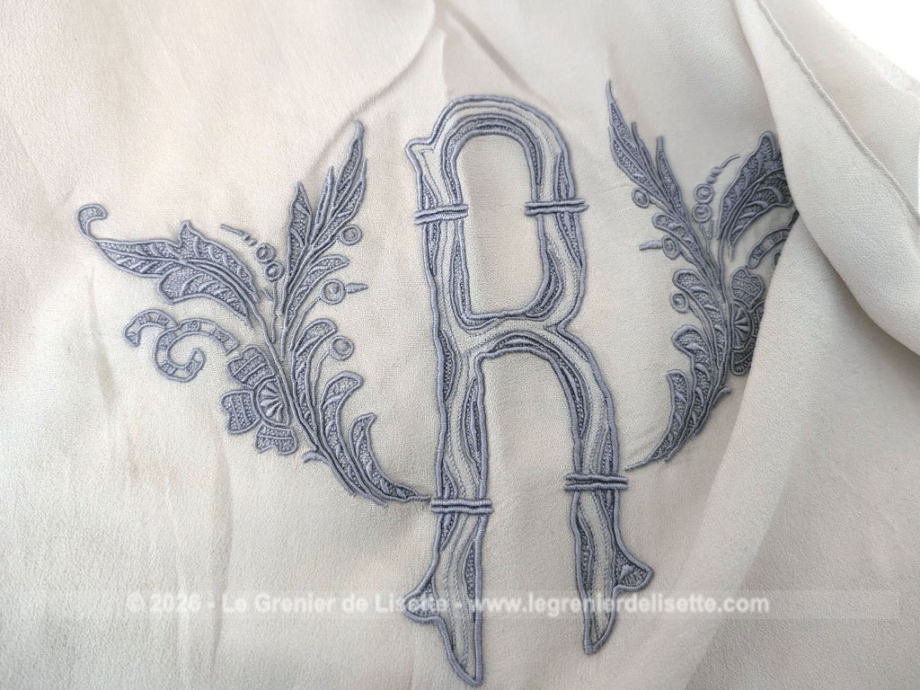 Fait main, voici une écharpe en voile de crêpe gris taupe de 80 x 154 cm, orné d'un grand R brodé et décoré aux extrémités d'un jour de Venise. Pour une écharpe discrète, originale et unique.