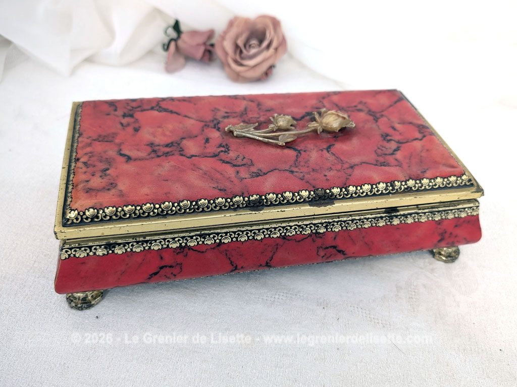 De forme rectangulaire, voici une ancienne belle boite métallique sérigraphiée en rouge, noir et or avec sur le couvercle une fleur dorée en relief et ses 4 pieds ouvragés