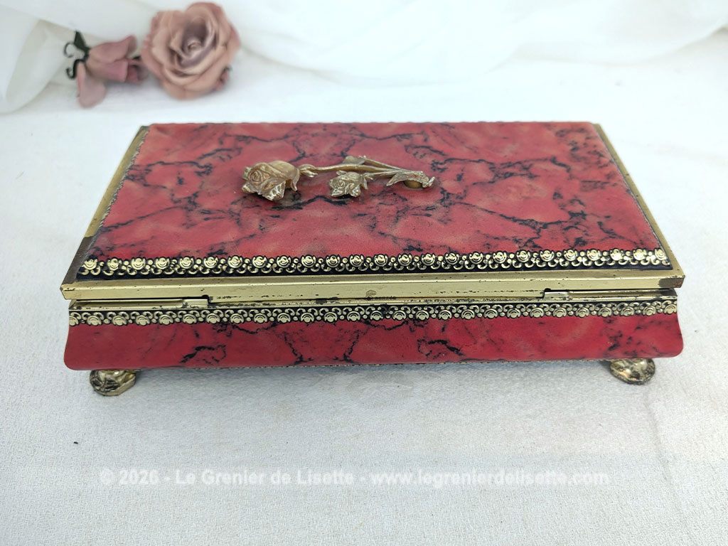 De forme rectangulaire, voici une ancienne belle boite métallique sérigraphiée en rouge, noir et or avec sur le couvercle une fleur dorée en relief et ses 4 pieds ouvragés