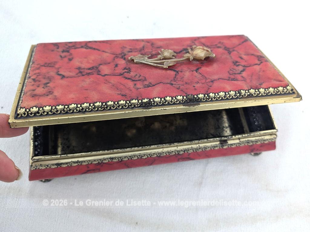 De forme rectangulaire, voici une ancienne belle boite métallique sérigraphiée en rouge, noir et or avec sur le couvercle une fleur dorée en relief et ses 4 pieds ouvragés