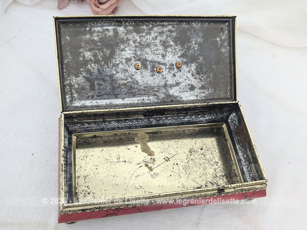 De forme rectangulaire, voici une ancienne belle boite métallique sérigraphiée en rouge, noir et or avec sur le couvercle une fleur dorée en relief et ses 4 pieds ouvragés