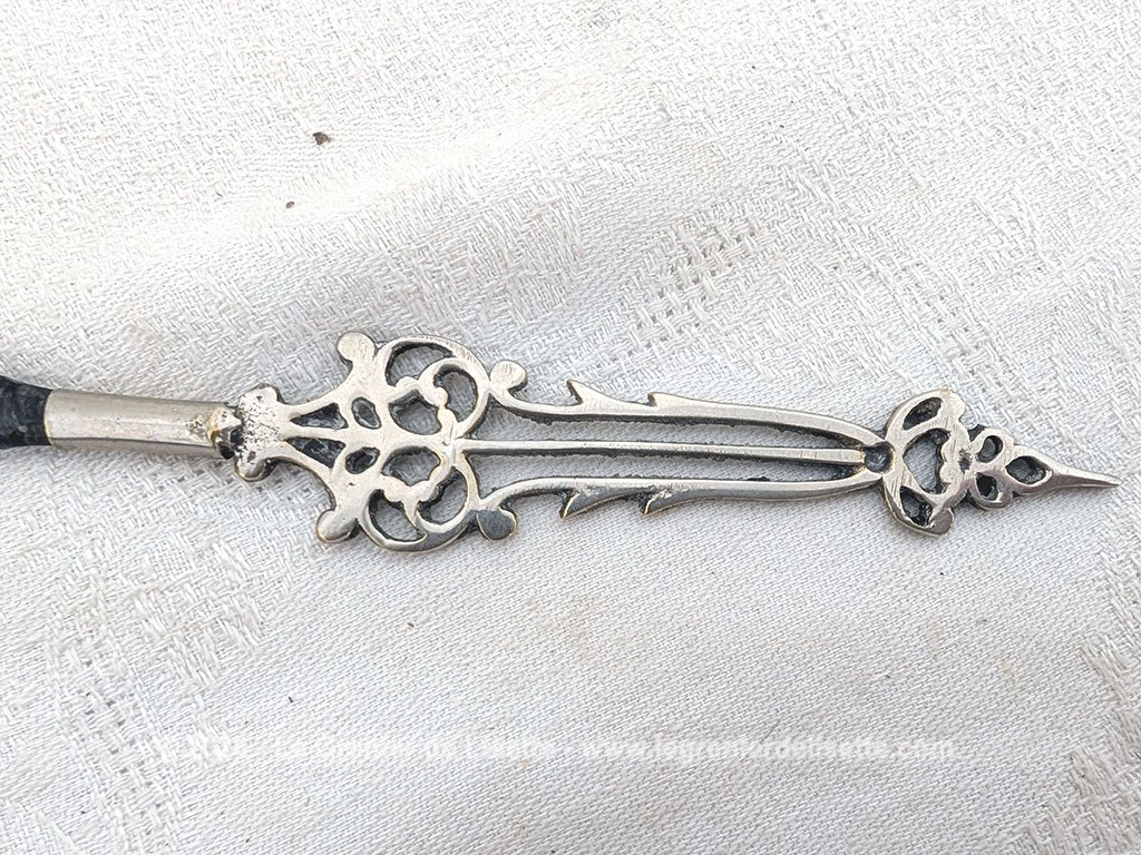 Voici un élégant coupe-papier des années 90, composé d'une lame en plastique épais noir, peut-être en bakélite à la ligne courbe et d'un manche en métal argenté aux motifs ciselés très décoratifs. Pièce artisanale pleine de charme qui remplit parfaitement sa fonction avec originalité.