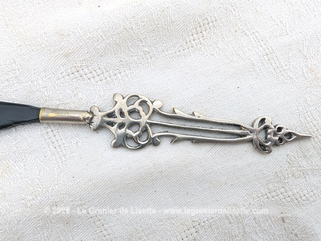 Voici un élégant coupe-papier des années 90, composé d'une lame en plastique épais noir, peut-être en bakélite à la ligne courbe et d'un manche en métal argenté aux motifs ciselés très décoratifs. Pièce artisanale pleine de charme qui remplit parfaitement sa fonction avec originalité.