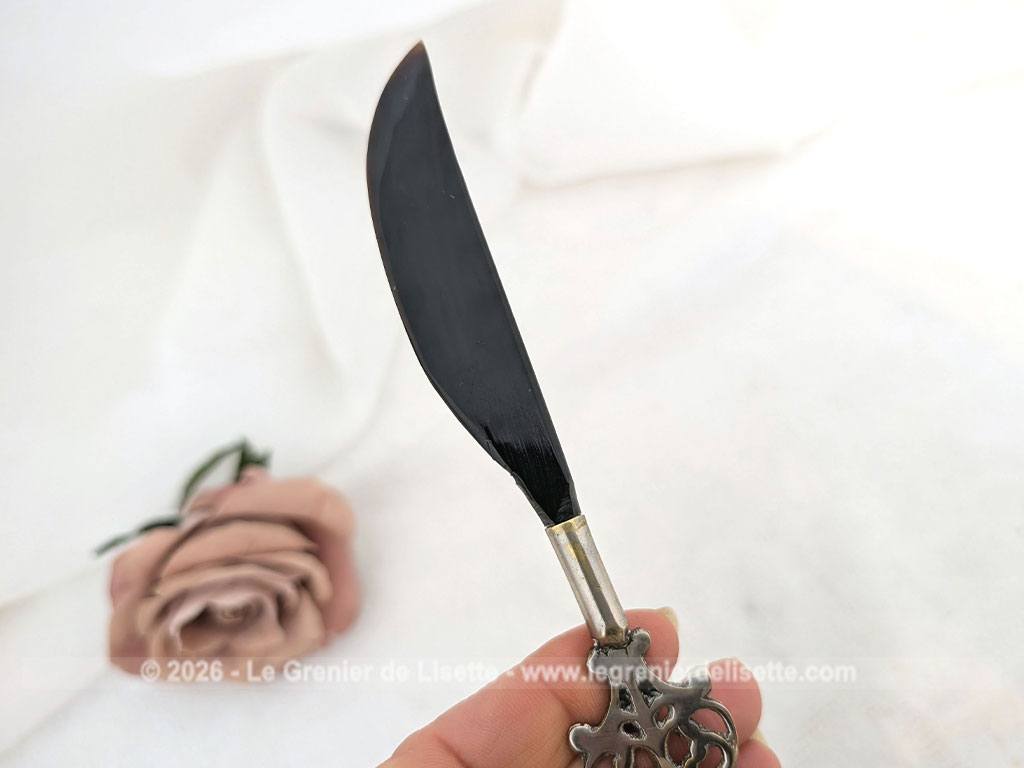 Voici un élégant coupe-papier des années 90, composé d'une lame en plastique épais noir, peut-être en bakélite à la ligne courbe et d'un manche en métal argenté aux motifs ciselés très décoratifs. Pièce artisanale pleine de charme qui remplit parfaitement sa fonction avec originalité.