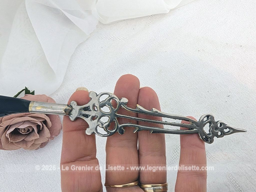 Voici un élégant coupe-papier des années 90, composé d'une lame en plastique épais noir, peut-être en bakélite à la ligne courbe et d'un manche en métal argenté aux motifs ciselés très décoratifs. Pièce artisanale pleine de charme qui remplit parfaitement sa fonction avec originalité.
