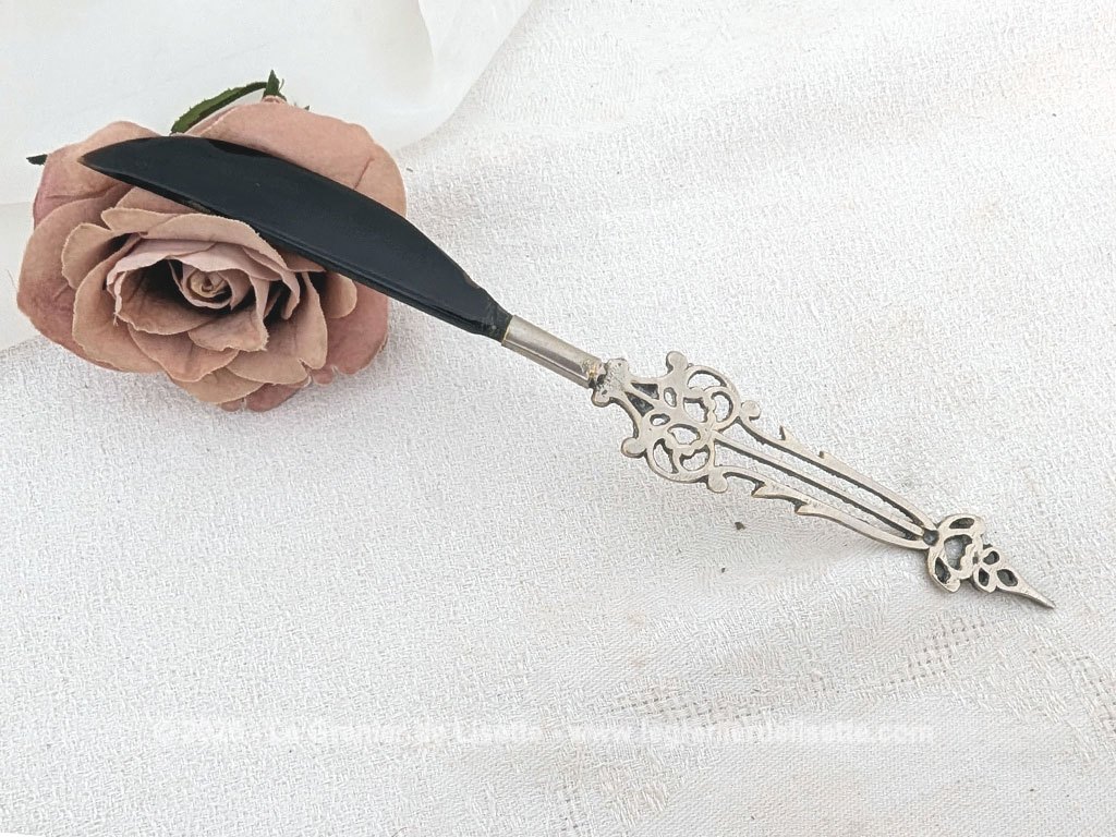Voici un élégant coupe-papier des années 90, composé d'une lame en plastique épais noir, peut-être en bakélite à la ligne courbe et d'un manche en métal argenté aux motifs ciselés très décoratifs. Pièce artisanale pleine de charme qui remplit parfaitement sa fonction avec originalité.