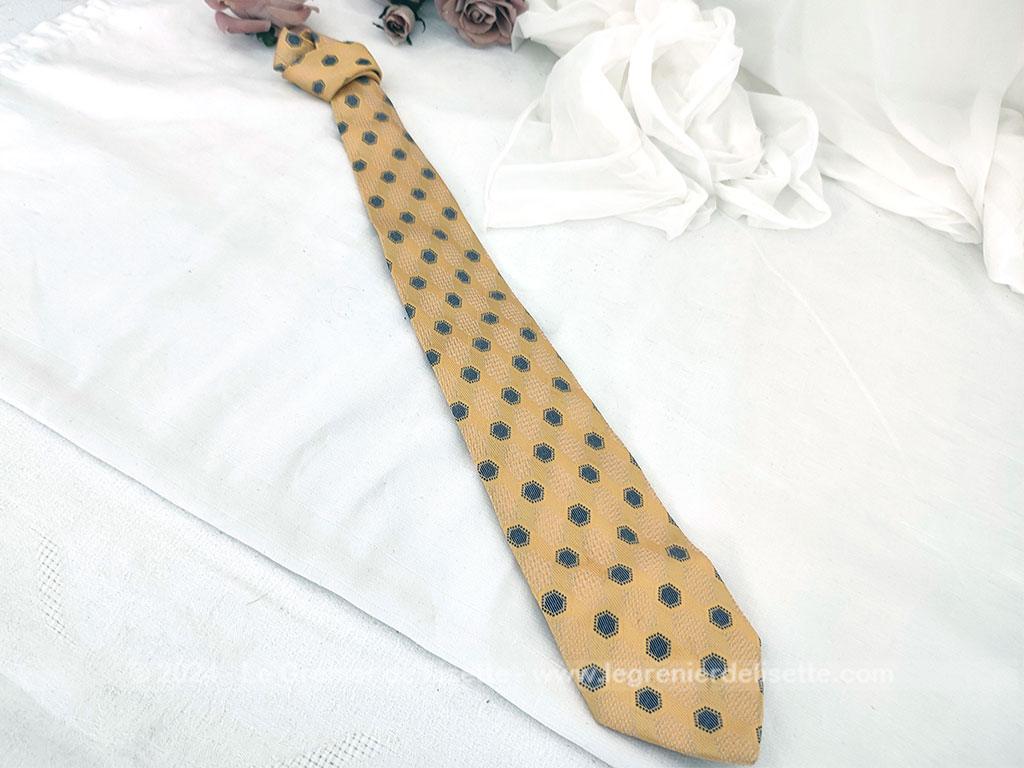 Elégante cravate vintage de la prestigieuse maison Pierre Cardin, 100% soie ocre jaune rehaussée de motifs géométriques tissés bleu et blanc, un style rétro chic très raffiné.