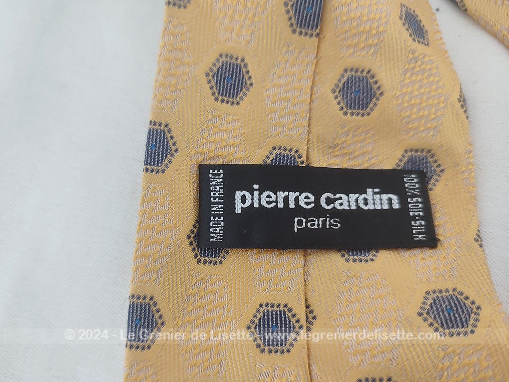 Elégante cravate vintage de la prestigieuse maison Pierre Cardin, 100% soie ocre jaune rehaussée de motifs géométriques tissés bleu et blanc, un style rétro chic très raffiné.
