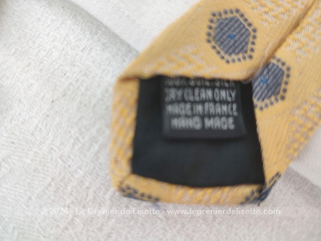 Elégante cravate vintage de la prestigieuse maison Pierre Cardin, 100% soie ocre jaune rehaussée de motifs géométriques tissés bleu et blanc, un style rétro chic très raffiné.