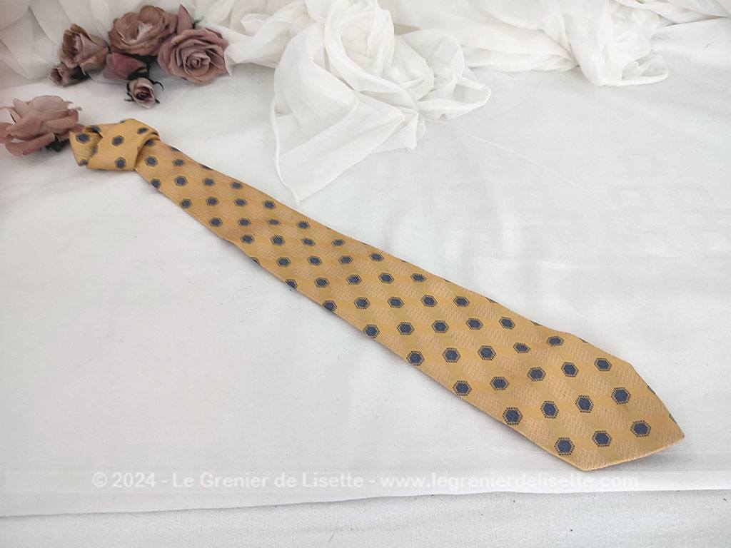 Elégante cravate vintage de la prestigieuse maison Pierre Cardin, 100% soie ocre jaune rehaussée de motifs géométriques tissés bleu et blanc, un style rétro chic très raffiné.