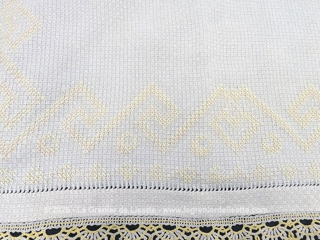 Ancien napperon original brodé de motifs géométriques au point de croix en fil jaune et bordé de dentelle aux fuseaux bicolore. Fait main et pièce unique.