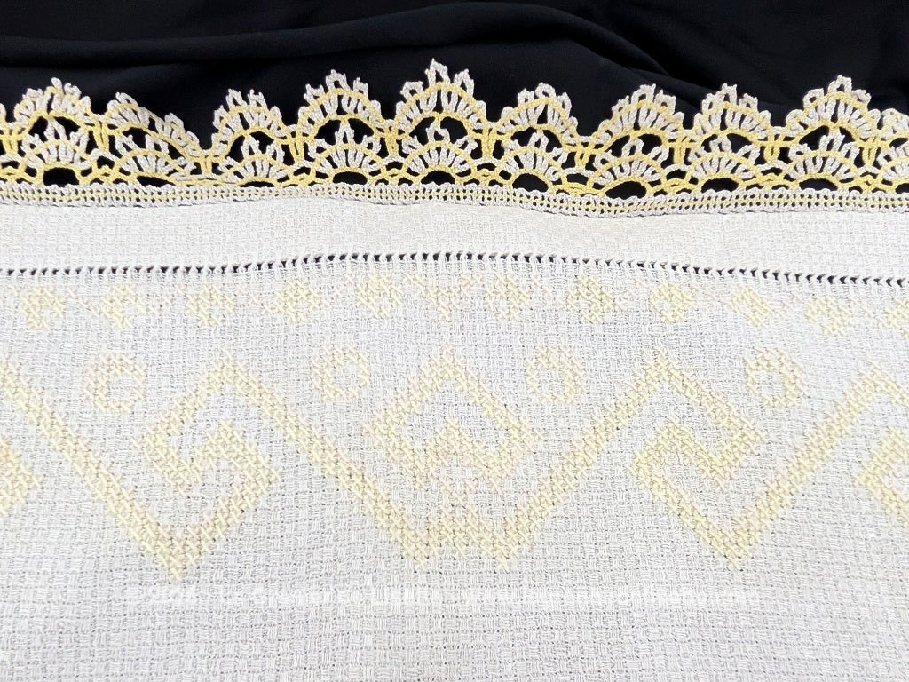 Ancien napperon original brodé de motifs géométriques au point de croix en fil jaune et bordé de dentelle aux fuseaux bicolore. Fait main et pièce unique.