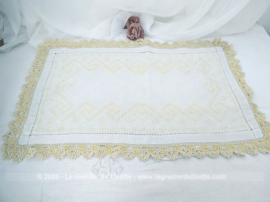 Ancien napperon original brodé de motifs géométriques au point de croix en fil jaune et bordé de dentelle aux fuseaux bicolore. Fait main et pièce unique.