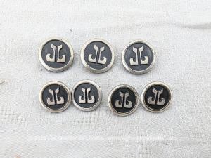 Voici un ensemble de sept boutons vintage au design élégant, 3 grands et 4 petits, ornés d'un monogramme JL stylisé en relief sur un fond noir avec un contour en métal argenté, parfaits pour la restauration d'une veste ou d'un blazer de style haute couture... vintage !