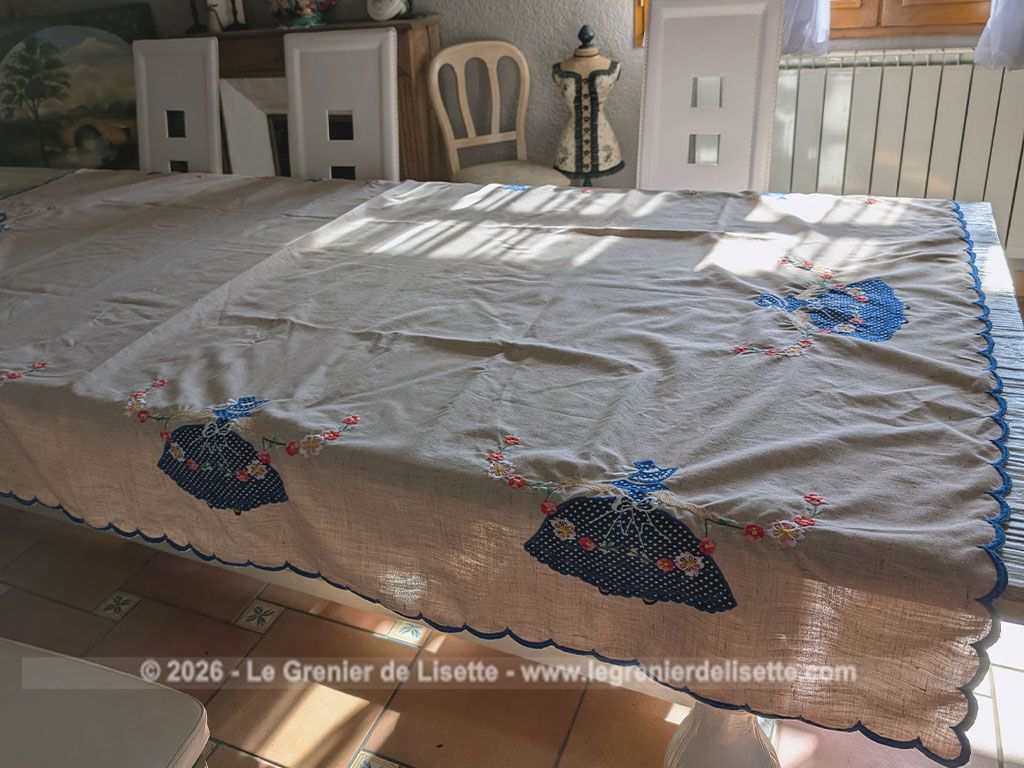 Sur 150 x 210 cm, voici une magnifique et grande nappe au look rétro et champêtre richement ornée de personnages aux robes en incrustations de tissu bleu à pois finement brodées. Idéale pour apporter une touche romantique et authentique à vos repas de famille.