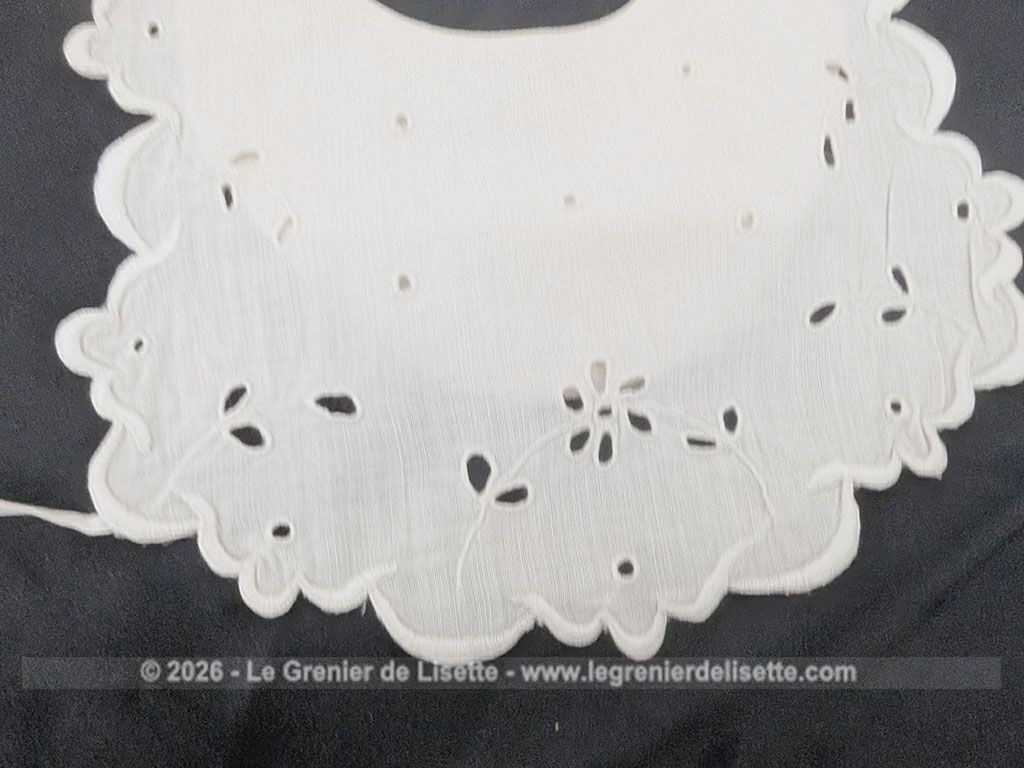 Voici un délicat bavoir ancien en délicat coton blanche, orné d'un beau travail de broderie anglaise aux motifs floraux avec des bordures festonnées. Deux liens d'origine pour l'attache au dos et un bouton au cou. Du beau linge ancien de qualité.