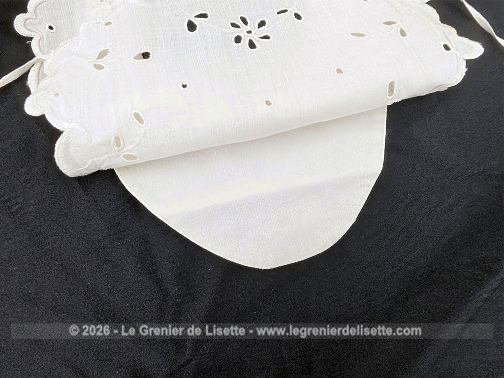 Voici un délicat bavoir ancien en délicat coton blanche, orné d'un beau travail de broderie anglaise aux motifs floraux avec des bordures festonnées. Deux liens d'origine pour l'attache au dos et un bouton au cou. Du beau linge ancien de qualité.