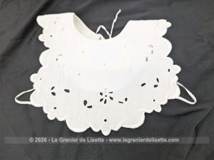 Voici un délicat bavoir ancien en délicat coton blanche, orné d'un beau travail de broderie anglaise aux motifs floraux avec des bordures festonnées. Deux liens d'origine pour l'attache au dos et un bouton au cou. Du beau linge ancien de qualité.