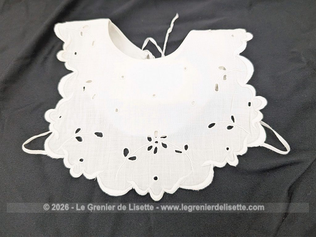 Voici un délicat bavoir ancien en délicat coton blanche, orné d'un beau travail de broderie anglaise aux motifs floraux avec des bordures festonnées. Deux liens d'origine pour l'attache au dos et un bouton au cou. Du beau linge ancien de qualité.