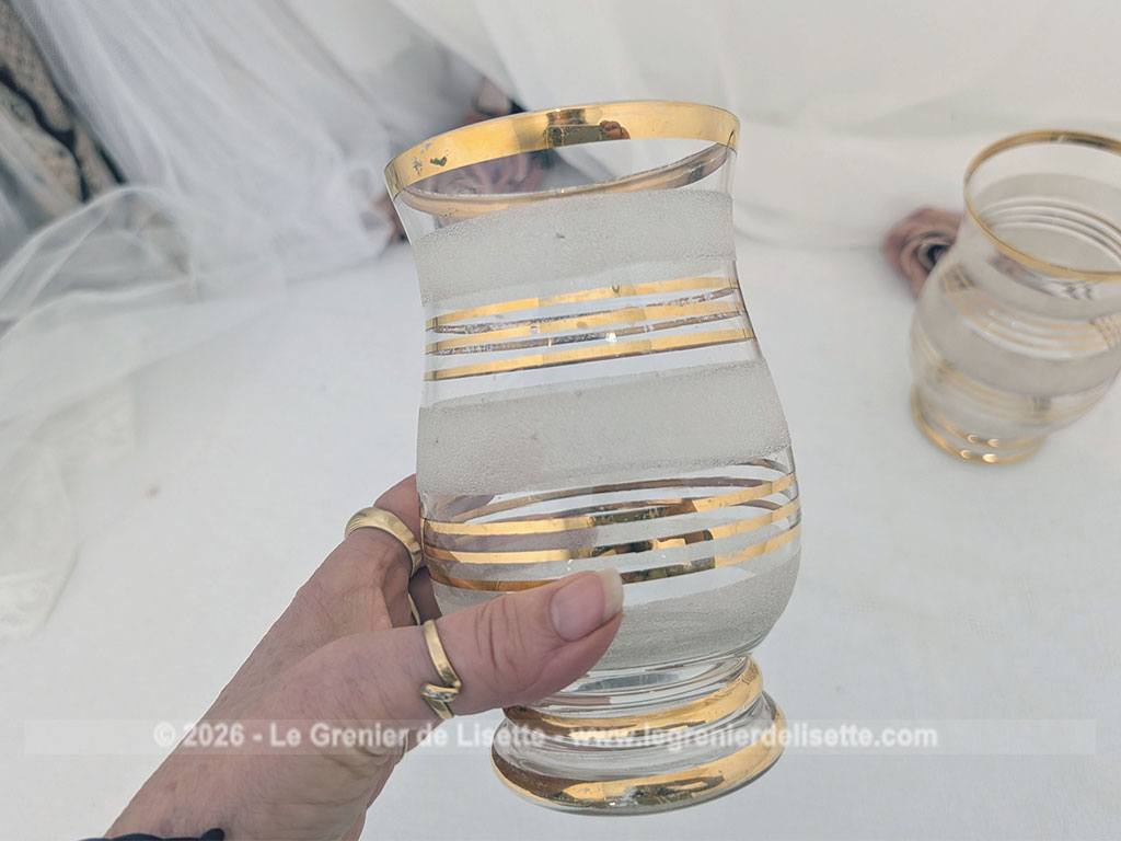 Sur 16 cm de haut et 9 cm de large, voici un duo de petits vases vintage qui jouent sur le contraste de matières avec une alternance de bandes de verre granité à l'aspect givré et de larges anneaux dorés.