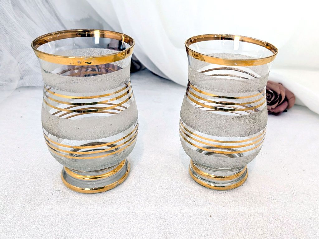 Sur 16 cm de haut et 9 cm de large, voici un duo de petits vases vintage qui jouent sur le contraste de matières avec une alternance de bandes de verre granité à l'aspect givré et de larges anneaux dorés.