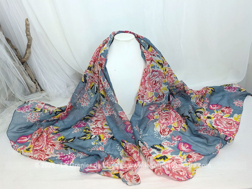 Sur 175 x 150 cm, voici un superbe foulard vintage en coton mélangé viscose, tout doux au toucher et decoré de gros bouquets de fleurs rosés sur un fond bleu gris. Etiquette