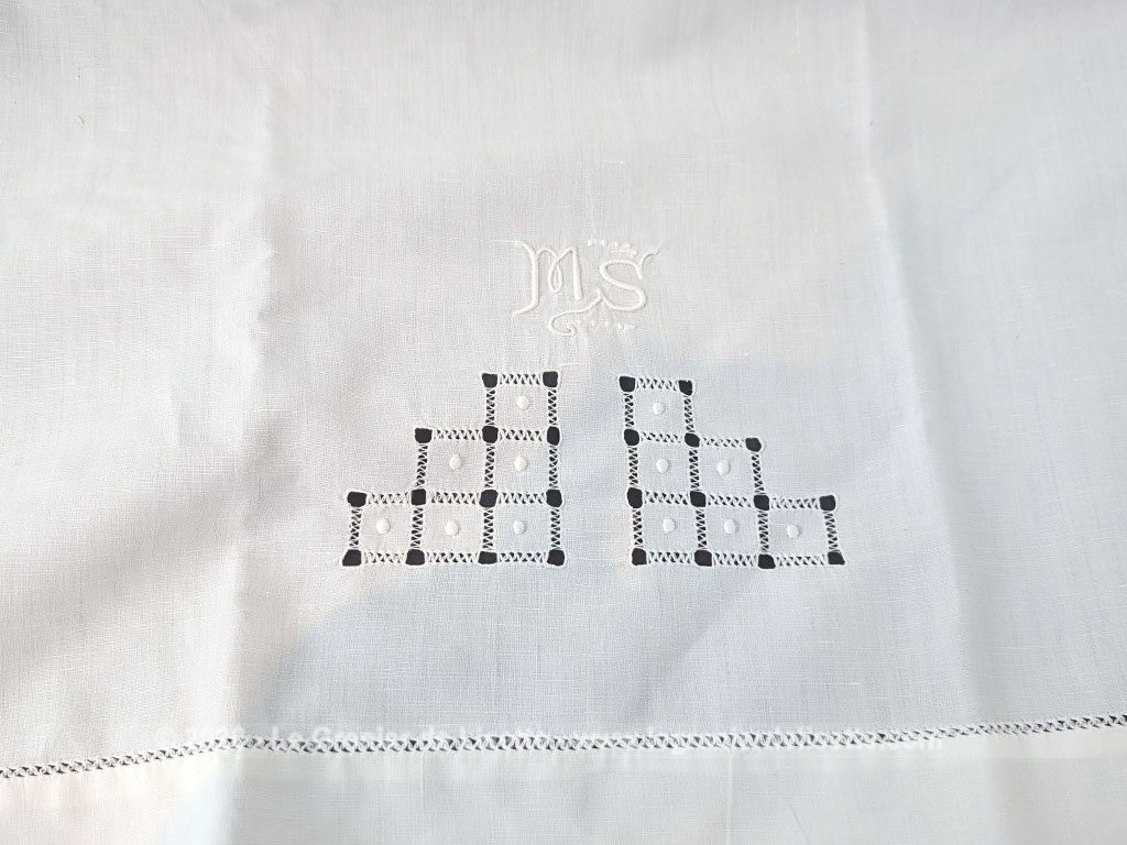 Voici un magnifique drap ancien de 90 x 126 cm pour berceau ou lit de bébé en coton blanc orné d'un superbe travail de jours de broderies géométriques et d'un élégant monogramme MS brodé à la main.