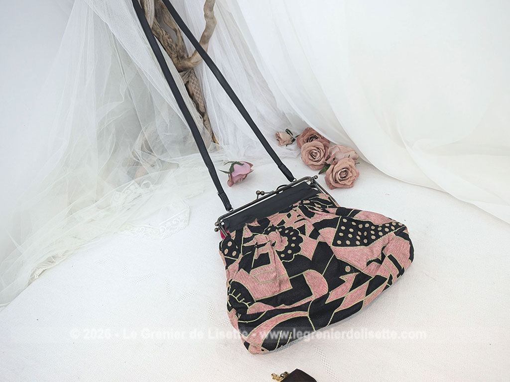 De la marque "Emma Blonde", voici un superbe sac minaudière vintage en tissu jacquard noir et rose très Art Déco, avec un haut en cuir noir et fermé par une armature en métal et doublé d'un satin fuchsia. A porterà l'épaule grâce à sa bandoulière en cuir noir ou à la main. Années 2000.
