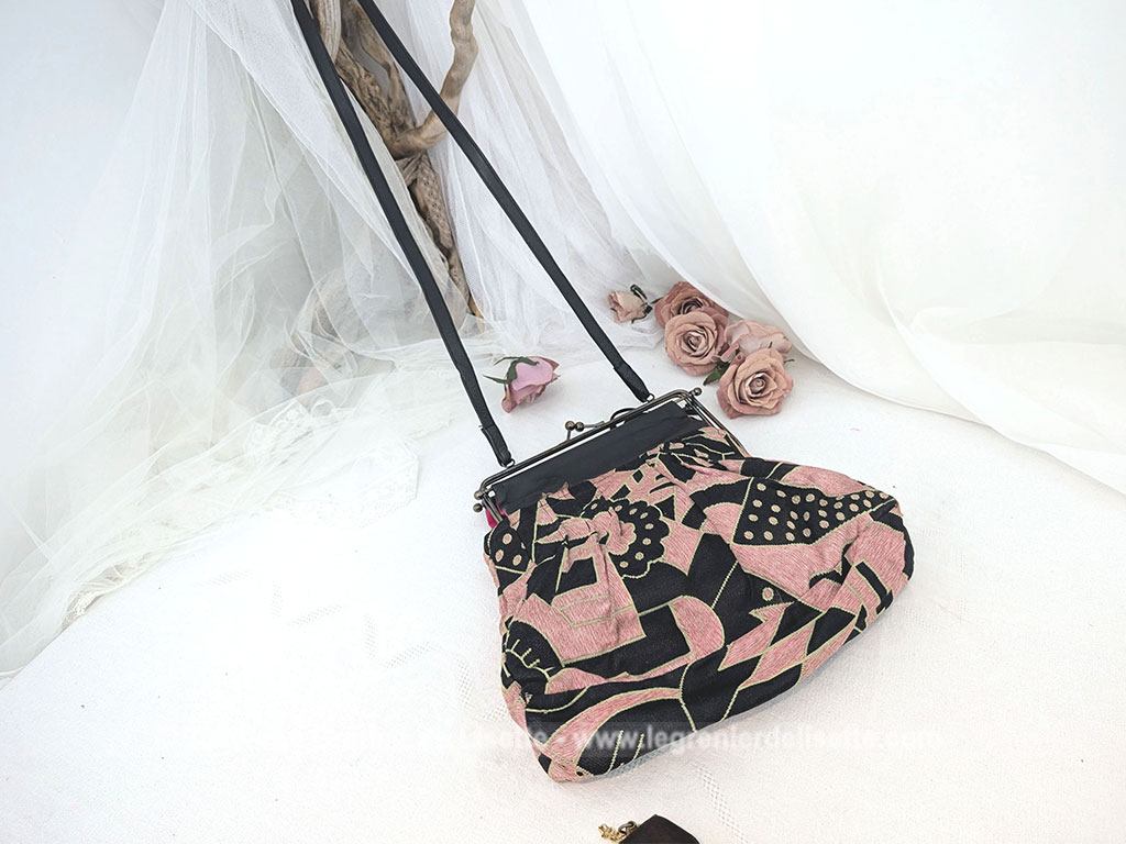 De la marque "Emma Blonde", voici un superbe sac minaudière vintage en tissu jacquard noir et rose très Art Déco, avec un haut en cuir noir et fermé par une armature en métal et doublé d'un satin fuchsia. A porterà l'épaule grâce à sa bandoulière en cuir noir ou à la main. Années 2000.