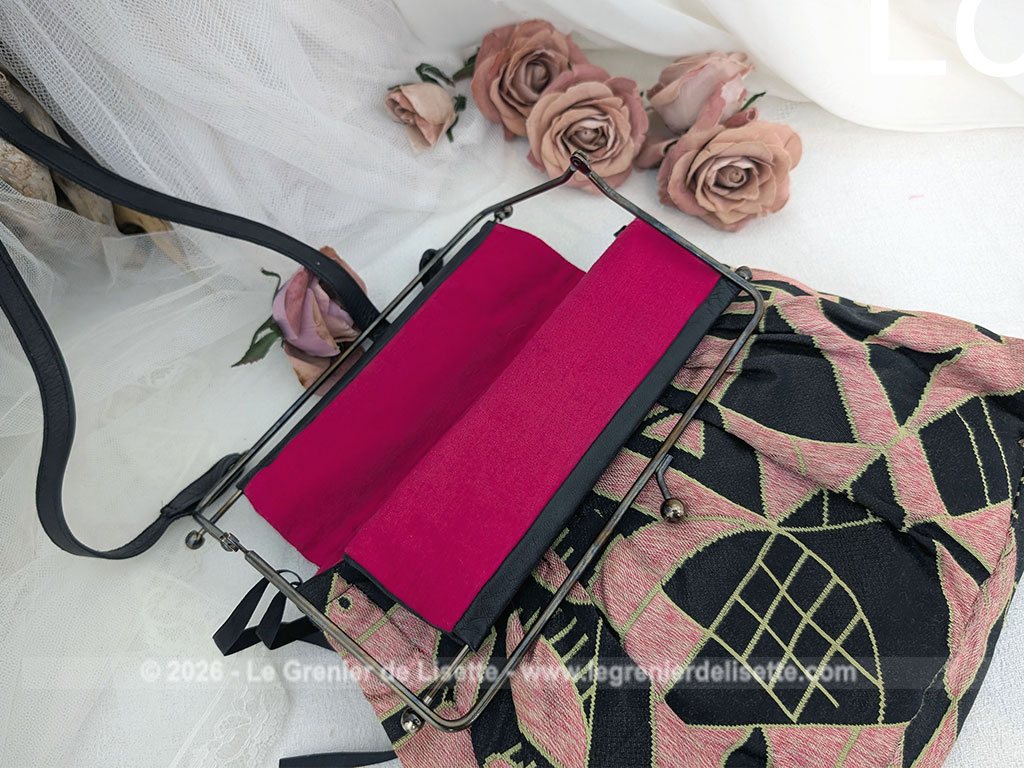 De la marque "Emma Blonde", voici un superbe sac minaudière vintage en tissu jacquard noir et rose très Art Déco, avec un haut en cuir noir et fermé par une armature en métal et doublé d'un satin fuchsia. A porterà l'épaule grâce à sa bandoulière en cuir noir ou à la main. Années 2000.