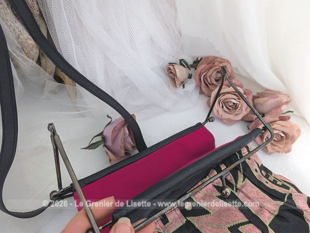 De la marque "Emma Blonde", voici un superbe sac minaudière vintage en tissu jacquard noir et rose très Art Déco, avec un haut en cuir noir et fermé par une armature en métal et doublé d'un satin fuchsia. A porterà l'épaule grâce à sa bandoulière en cuir noir ou à la main. Années 2000.
