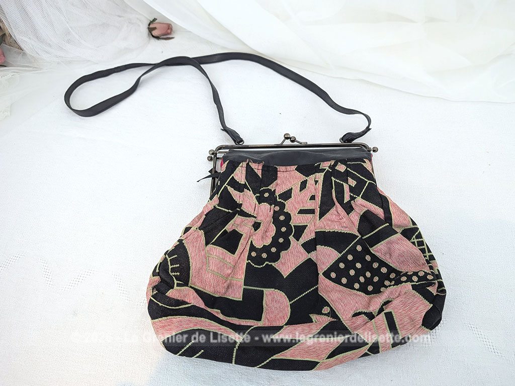 De la marque "Emma Blonde", voici un superbe sac minaudière vintage en tissu jacquard noir et rose très Art Déco, avec un haut en cuir noir et fermé par une armature en métal et doublé d'un satin fuchsia. A porterà l'épaule grâce à sa bandoulière en cuir noir ou à la main. Années 2000.