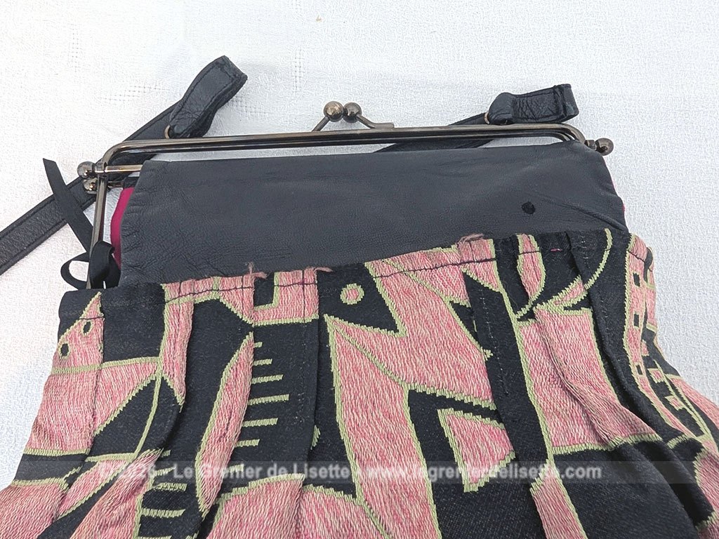 De la marque "Emma Blonde", voici un superbe sac minaudière vintage en tissu jacquard noir et rose très Art Déco, avec un haut en cuir noir et fermé par une armature en métal et doublé d'un satin fuchsia. A porterà l'épaule grâce à sa bandoulière en cuir noir ou à la main. Années 2000.