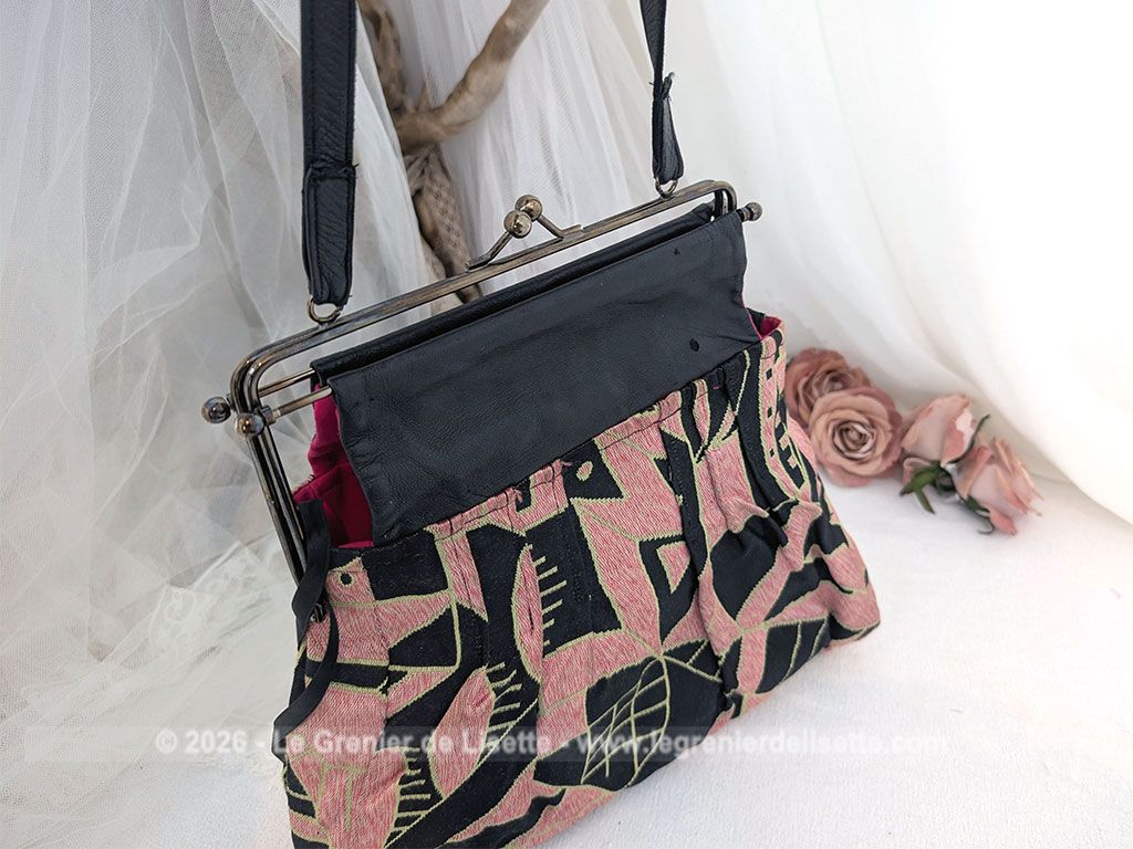 De la marque "Emma Blonde", voici un superbe sac minaudière vintage en tissu jacquard noir et rose très Art Déco, avec un haut en cuir noir et fermé par une armature en métal et doublé d'un satin fuchsia. A porterà l'épaule grâce à sa bandoulière en cuir noir ou à la main. Années 2000.