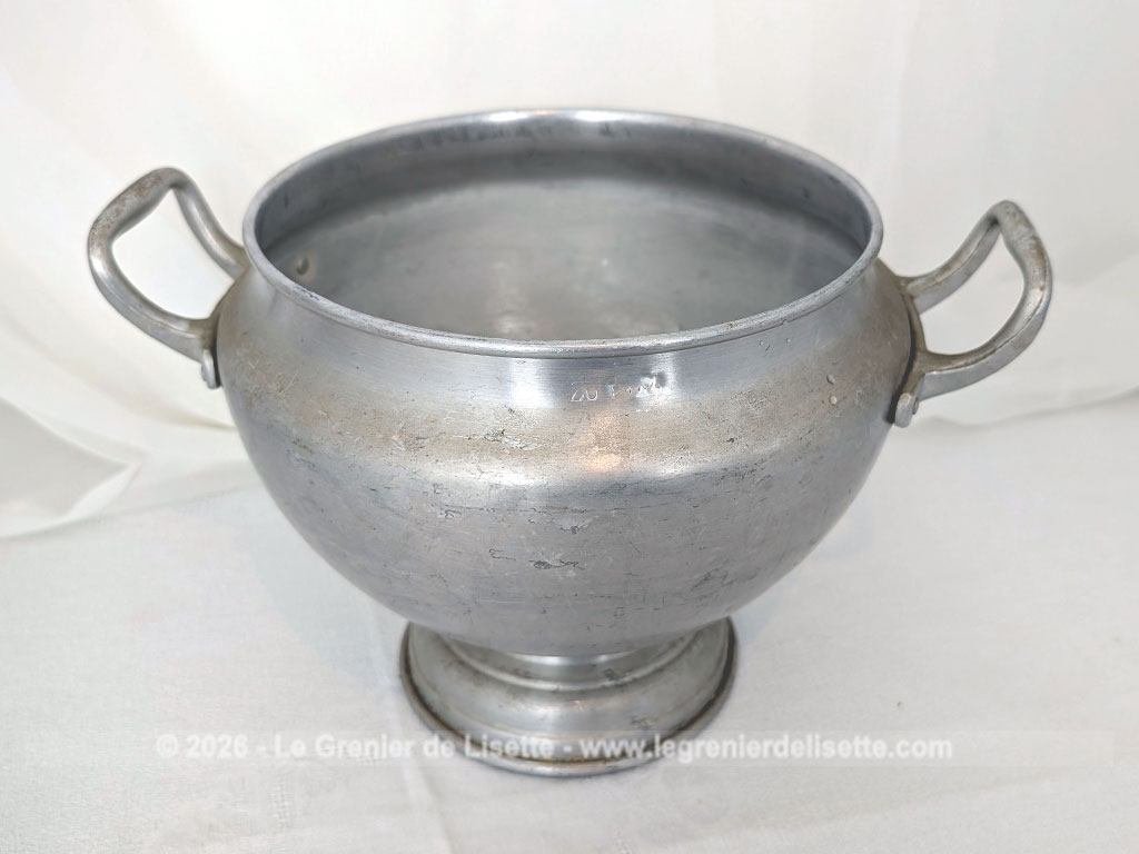 Voici un corps de soupière vintage en aluminium au charme rustique et authentique avec sa ligne ventrue qui repose sur un élégant piédouche et ses deux anses rivetées. Proposée sans son couvercle elle se transforme idéalement en un grand saladier, cache pot ou un centre de table de caractère.