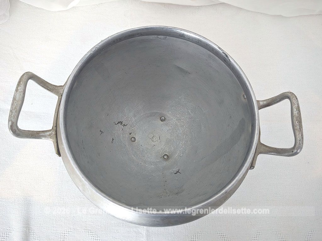 Voici un corps de soupière vintage en aluminium au charme rustique et authentique avec sa ligne ventrue qui repose sur un élégant piédouche et ses deux anses rivetées. Proposée sans son couvercle elle se transforme idéalement en un grand saladier, cache pot ou un centre de table de caractère.
