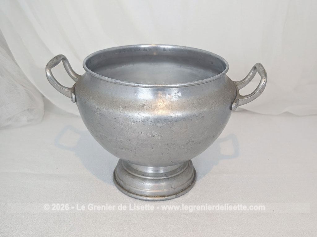 Voici un corps de soupière vintage en aluminium au charme rustique et authentique avec sa ligne ventrue qui repose sur un élégant piédouche et ses deux anses rivetées. Proposée sans son couvercle elle se transforme idéalement en un grand saladier, cache pot ou un centre de table de caractère.
