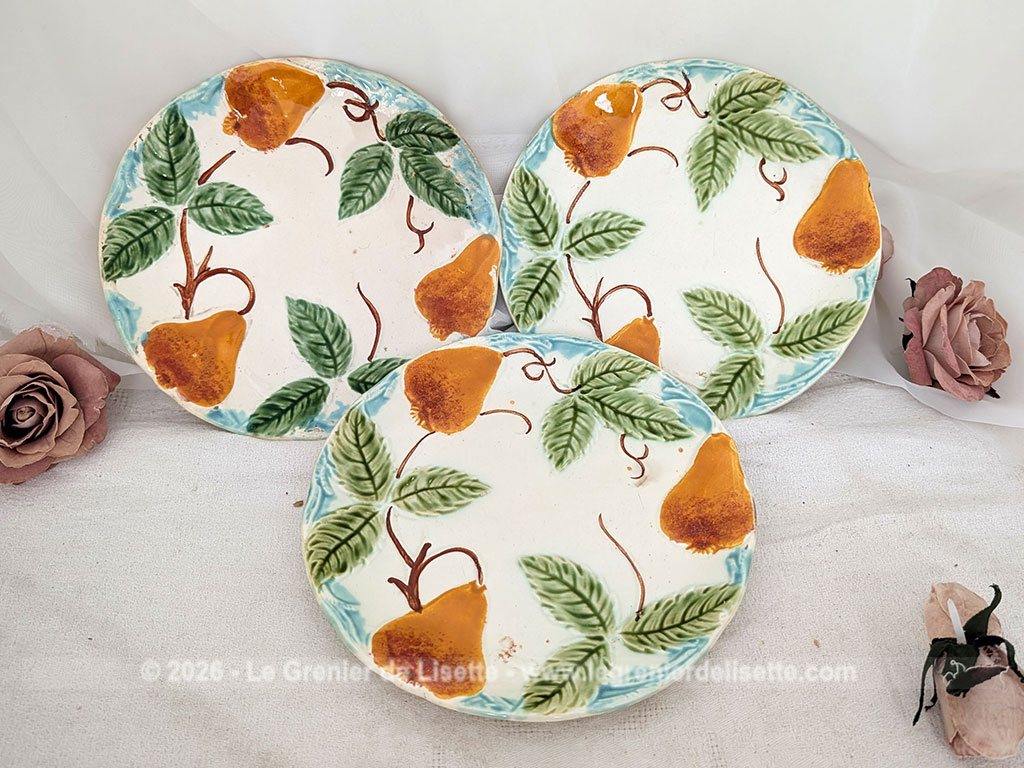 Voici un charmant lot de trois assiettes anciennes en barbotine du tout début du XXe siècle décorées de poires gourmandes aux nuances chaudes et de feuillages verts bien ciselés, souligné par une bordure azur.