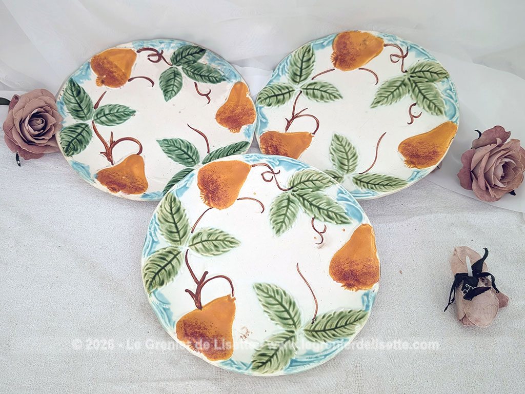 Voici un charmant lot de trois assiettes anciennes en barbotine du tout début du XXe siècle décorées de poires gourmandes aux nuances chaudes et de feuillages verts bien ciselés, souligné par une bordure azur.